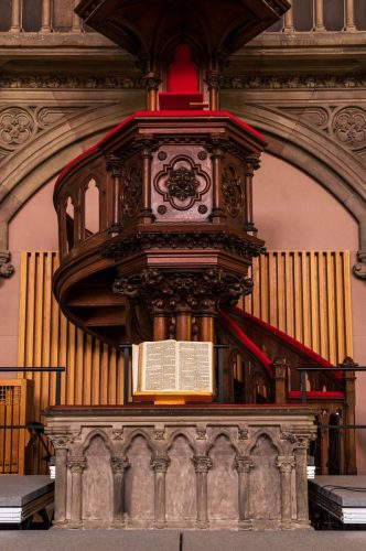 Beautifully carved wooden pulpit with an open Bible in a historic Mulhouse church.