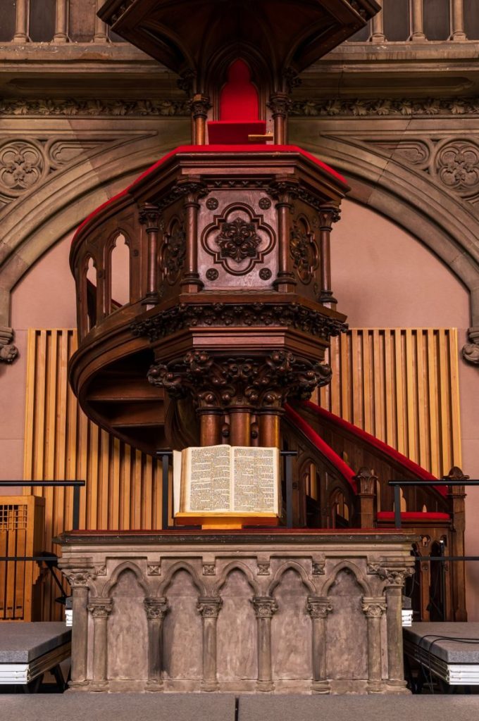 Beautifully carved wooden pulpit with an open Bible in a historic Mulhouse church.