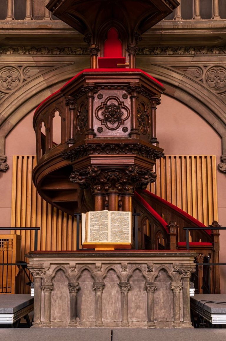 Beautifully carved wooden pulpit with an open Bible in a historic Mulhouse church.
